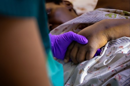 U.S. Army Capt. Michelle Smith, an emergency nurse (66T) assigned to the 30th Medical Brigade, holds the hand of a Burundian patient while her fistula gets cleaned during the medical readiness exercise (MEDREX) in Bujumbura, Burundi, July 22,...