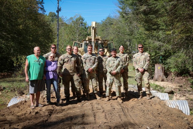 North Carolina National Guardsmen with the 113th Sustainment Brigade and the 30th Armored Brigade Combat Team pose for a photo with Rick and Carla Brite after a bridge-building operation at their residence in Nebo, N.C., Oct. 9, 2024. Guardsmen built bridges to connect roads for local residents following Tropical Storm Helene.(U.S. Army National Guard photo by Staff Sgt. Hannah Tarkelly).