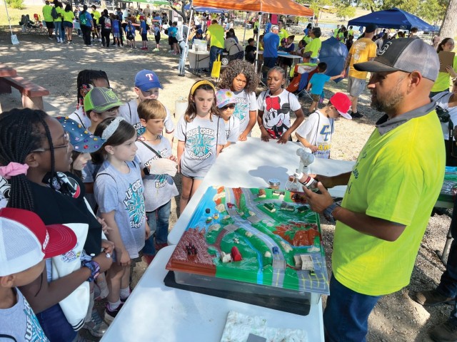 Dan Gomez, an environmental protection specialist with the Fort Cavazos Directorate of Public Works, discusses storm water pollution prevention with third graders at the Keep Copperas Cove Beautiful Eco Harvest event Oct. 4 at Copperas Cove City Park at Copperas Cove, Texas. (U.S. Army photo by Christine Luciano, Fort Cavazos DPW Environmental)