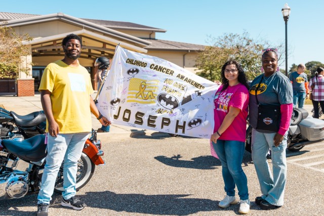 Participants of the 7th annual post-wide motorcycle ride for cancer hold the childhood cancer awareness flag before the ride Oct. 18 on Fort Novosel.