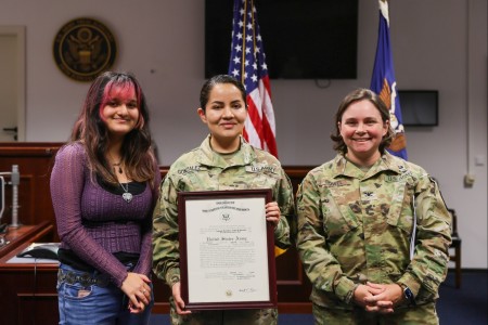 1st Lt. Perla Y. Gonzalez (center) poses for a photo with her daughter, Yelis (left), Col. Katherine S. Gowel, the 21st Theater Sustainment Command SJA, after being promoted from Sgt. 1st Class during a promotion ceremony hoste...