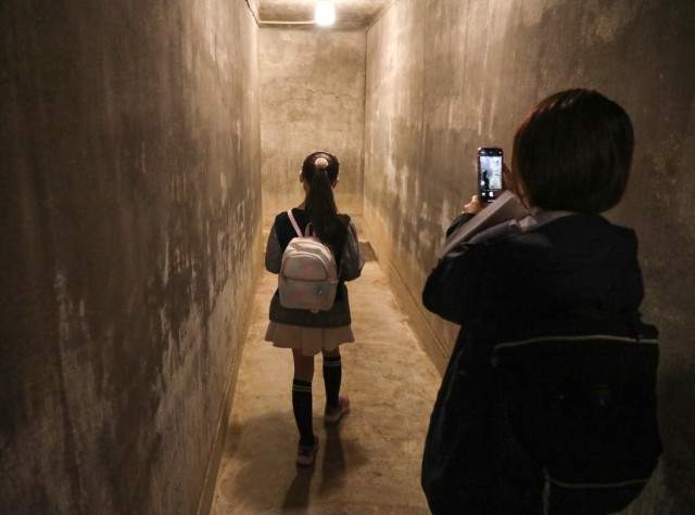 Miyuki Iiyama, right, an administrative specialist for the Directorate of Human Resources, takes a photo of her daughter, Marina, as they tour a bunker built for former Emperor Hirohito during the &#34;Bring Your Kids to Work Day&#34; event at...