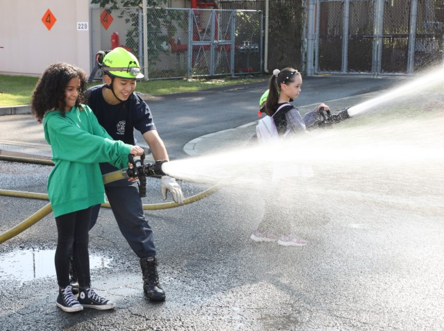 Camp Zama firefighters help children spray water from fire hoses during the &#34;Bring Your Kids to Work Day&#34; event at Camp Zama, Japan, Nov. 4, 2024. Dozens of children belonging to Camp Zama personnel visited the installation to see the...