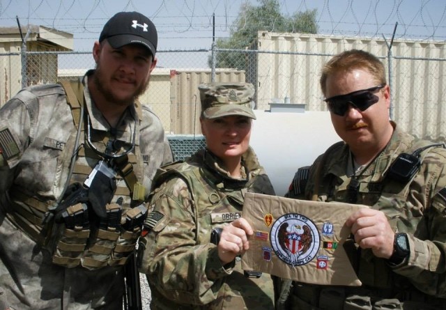 Master Sgt. Melissa O&#39;Brien displays a mobile training team miniature guidon while supporting Operation Iraqi Freedom in 2011. She provided critical intelligence for Soldiers on the battlefield.  