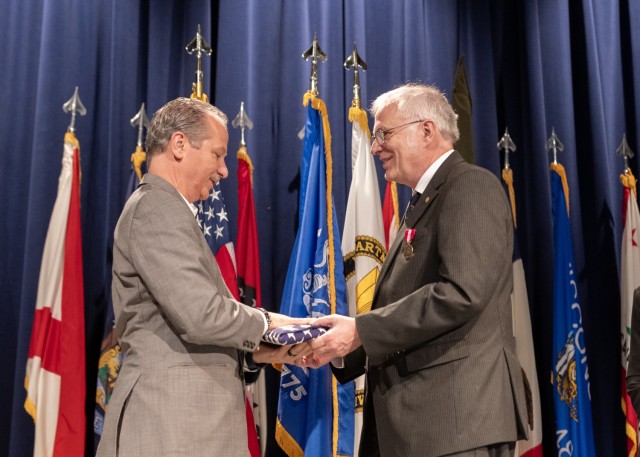 PICATINNY ARSENAL, N.J. - Chris Grassano, Director of the U.S. Army Combat Capabilities Development Command (DEVCOM) Armaments Center, presents Brian E. Fuchs, a senior research scientist, with a U.S. flag at Fuchs' retirement ceremony on Nov. 8.