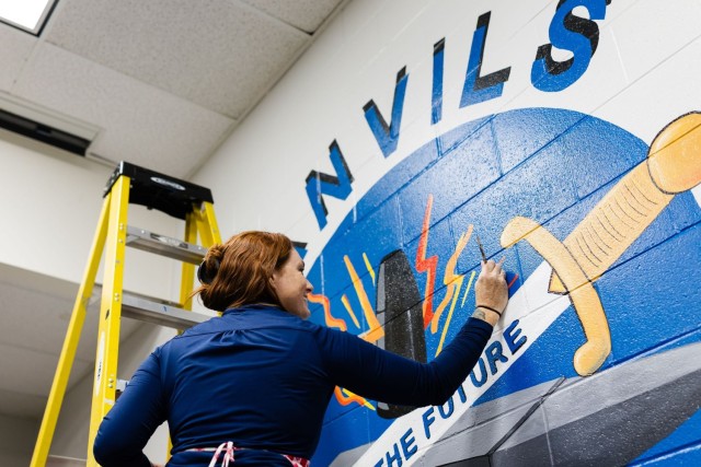 Carolyn Brown, Fort Novosel spouse and local artist, paints an updated mural of the A Co. 1-145th logo in an Aviation CCC classroom on Fort Novosel Nov. 20.