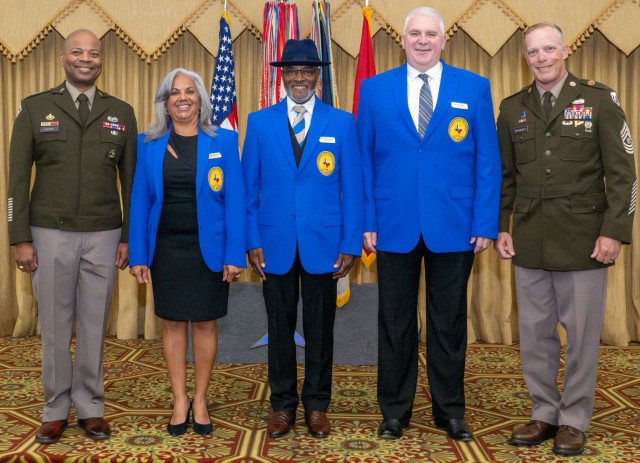 Five people standing side by side pose for a picture with smiles.