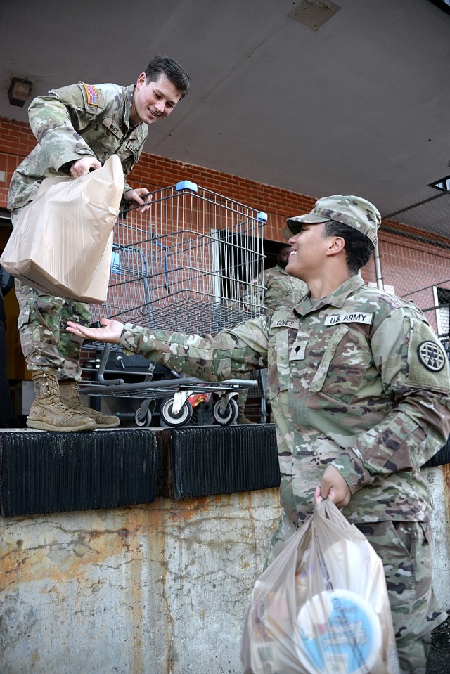 Cpl. Jonathan White, Headquarters, U.S. Disciplinary Barracks Battalion (Corrections), hands bags filled with potatoes, celery, rolls, pies and other food items to Spc. David Gomes, Headquarters, Midwest Joint Regional Correctional Facility Battalion (Corrections), as they help distribute Thanksgiving meals to soldiers’ families Nov. 19, 2024, at the Fort Leavenworth Commissary loading dock at Fort Leavenworth, Kansas. The meals, which also included a turkey with size determined by the number of dependents, were possible because of chapel community offerings and Commissary shoppers’ donations. The Religious Service Organization organized the meal distribution and provided meals to 100 soldiers, selected by need/rank by their command teams, from the Army Corrections Brigade, Medical Department Activity, Special Troops Battalion, Staff Judge Advocate and Kansas City Recruiting Battalion. Volunteers from several units and organizations, including the RSO, Association of the United States Army, Fort Leavenworth Spouses’ Club, Sergeant Audie Murphy Club, Fort Leavenworth Commissary and chapel community helped with the distribution. The RSO will distribute holiday meals for soldiers again Dec. 17. Photo by Prudence Siebert/Fort Leavenworth Lamp