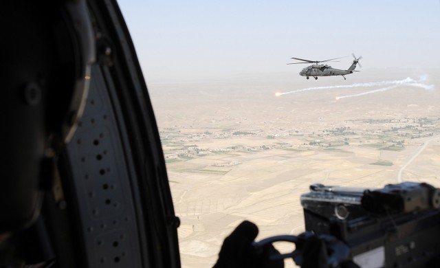 Two UH-60L Black Hawk helicopters from Company B, Task Force Attack, 1st Air Cavalry Brigade, attached to 10th Combat Aviation Brigade, 10th Mountain Division, “pop flares” while flying over Afghanistan to transport personnel July 20. Flares...