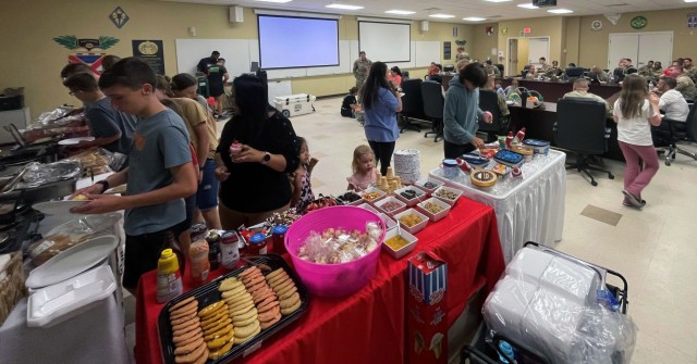 Families of drill sergeants at Fort Jackson, South Carolina, enjoy a potluck dinner as part of the first 72 hours. Lt. Col. Tony Messenger, 3rd Squadron commander, Second Security Force Assistance Brigade, Fort Liberty, North Carolina, and his family transformed the conference room in the drill sergeant's battalion, so the drill sergeants who were on duty could rotate through to see their families and get a home cooked meal Dec. 16, 2023. The Messengers cooked the breakfast meal and worked with volunteer families to bring the potluck food to share. (Courtesy photo)