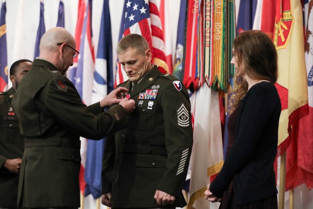 U.S. Army Col. Joesph Messina, Chief of Strategic Initiative Group for the Assistant Secretary of the Army for manpower and reserve affairs, and Deputy Chief of Staff for Army G-1, pins Command Sgt. Maj. Garth Newell with the Legion of Merit....