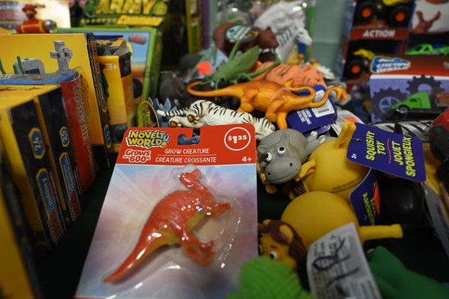 A haphazard pile of toys with tags on them sit , sitting between neat rows of toys in boxes.