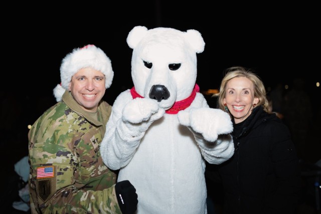Col. John P. Miller III, Fort Novosel garrison commander, and his spouse Ms. Mollie Miller, ring in the holiday season with Sgt. Ted. E. Bear during the annual Winterfest event Dec. 7, 2024.