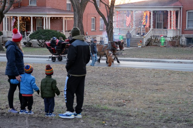 Kimberly McMenamin, co-author of “Hello, Home Fort Leaveworth,” Maj. Marc McMenamin, Command and General Staff Officer Course student, and their 2-year-old sons James and Tyler watch a team from Duncan Carriages take community members around...