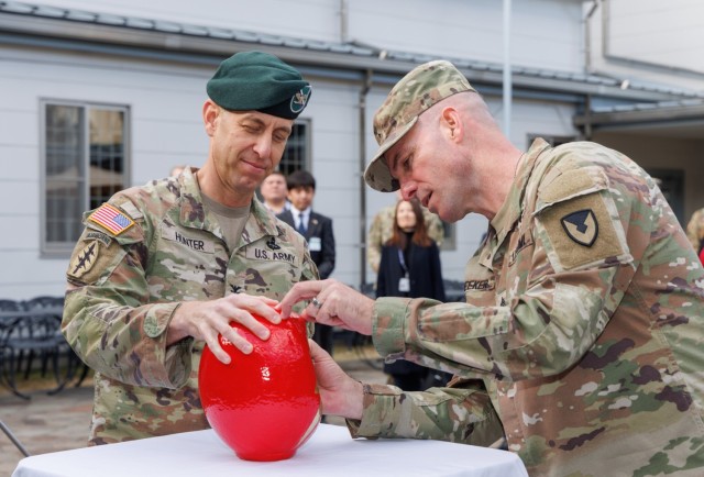 Col. Marcus Hunter, left, commander of U.S. Army Garrison Japan, watches Command Sgt. Maj. Rick Meeker, right, paint in one of the eyes of a &#34;daruma&#34; doll during a ceremony at Camp Zama, Japan, Dec. 12, 2024. Meeker assumed responsibility of the garrison&#39;s senior enlisted leader role from Command Sgt. Maj. David A. Rio, who plans to take a position at Fort Gregg-Adams, Virginia.