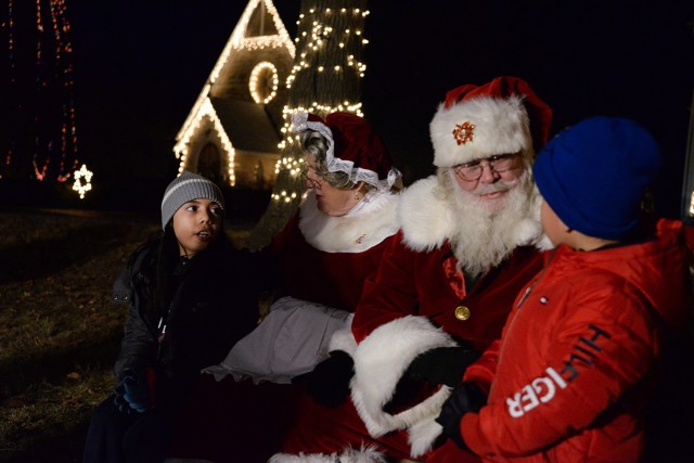 Ten-year-old Juanita Reges, from Colombia, translates Christmas wishes for her 4-year-old brother, Juan, as they visit with Mrs. Claus and Santa Claus at the annual holiday lighting event Dec. 6, 2024, at Zais Park on Fort Leavenworth, Kansas....