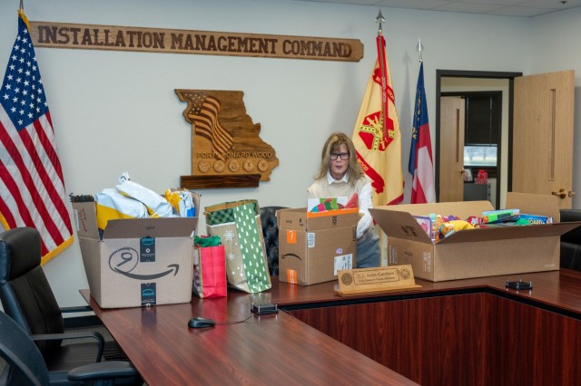 Connie Porterfield, U.S. Army Garrison Fort Leonard Wood executive officer, collects and organizes gifts donated through the Garrison Gives program on the garrison’s conference room table Dec. 16 in Hoge Hall.