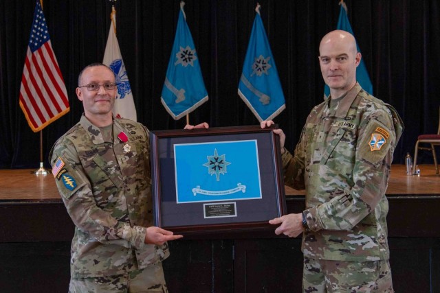 Brig. Gen. Rhett R. Cox, right, the commanding general of Army Counterintelligence Command, holds presents a gift to outgoing Command Chief Warrant Officer Aaron Skiles before the command chief warrant officer change of responsibility ceremony at...
