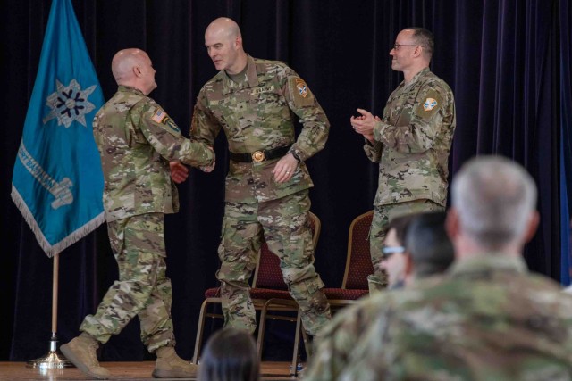 Brig. Gen. Rhett R. Cox, center, the commanding general of Army Counterintelligence Command, shakes hands with Chief Warrant Officer 5 Jamie Turner, the incoming command chief warrant officer, alongside outgoing Command Chief Warrant Officer Aaron...