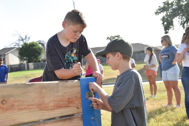 One boy tightens a bolt while the other holds it in place.