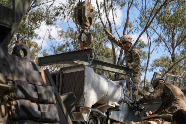 SGT Caelib Gustafson, an M1A2 Abrams tank mechanic assigned to Comanche Company, 4th Battalion, 6th Infantry Regiment, helps guide the crane operator as they lower an engine into the body of an M1A2 Abrams tank at the Townsville Field Training...