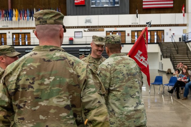 U.S. Army Capt. Ricky Kuhn, 817th Engineer Company, Sapper, outgoing commander, left, watches as Lt. Col. Steven Bohl, 164th Engineer Battalion commander, passes the 817th Engineer Company, Sapper, guidon to his older brother, Capt. Toby Kuhn, during the change of command ceremony in Jamestown, North Dakota, Jan. 12, 2025. The brothers enlisted into the U.S. Army at different times, but both commissioned in 2017. (U.S. National Guard photo by Spc. Anna Welchel)