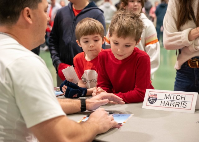 Brothers, Marshall and Everett Garrison, watch as Mitch Harris, St. Louis Cardinals former pitcher, signs his autograph for them during the Cardinals Caravan visit to Fort Leonard Wood Jan. 17 at Nutter Field House.