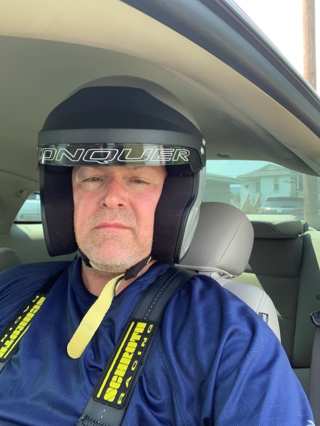 A person sits in a car with a helmet on.