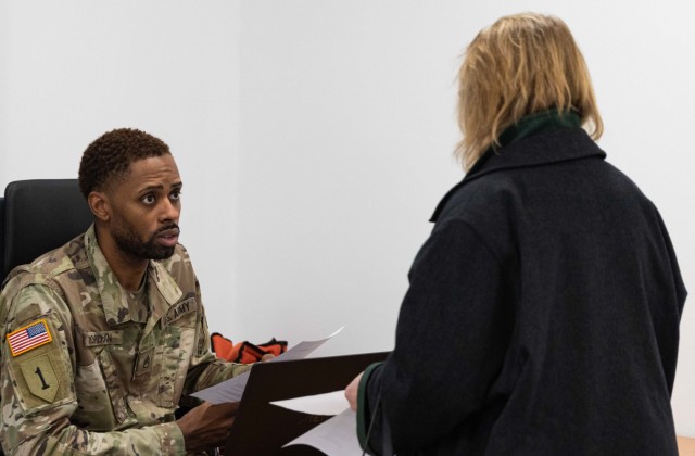 Army Staff Sgt. Jeremy J. Jordan, a physical security specialist with the Wiesbaden Vehicle Registration Office assists a customer with her vehicle registration paperwork.