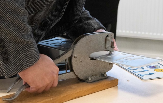 A customer at the Wiesbaden Vehicle Registration Office punches holes in a new license plate.