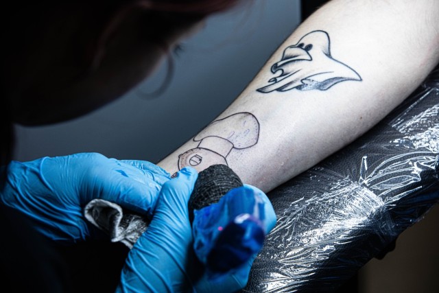 Kinga Nemeth, an Infamous Ink tattoo artist, gives a tattoo to a customer during a grand opening event at Fort Stewart, Georgia, Jan. 31. Infamous Ink is open seven days a week from 11 a.m. to 6 p.m., and is located next to the Commissary on base....