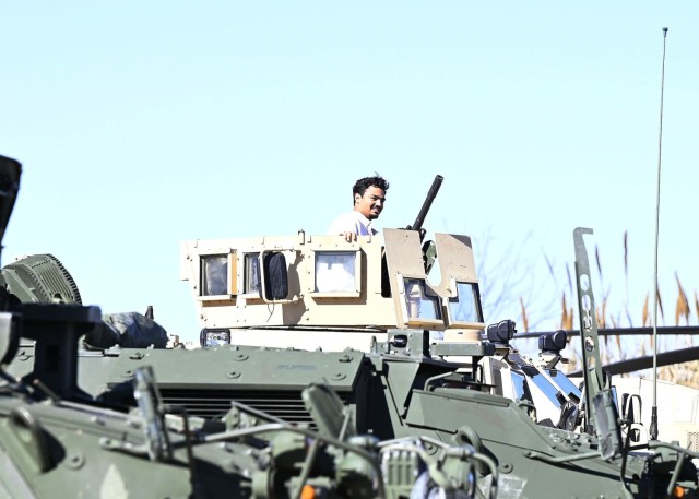 A man looks out from atop a military vehicle.