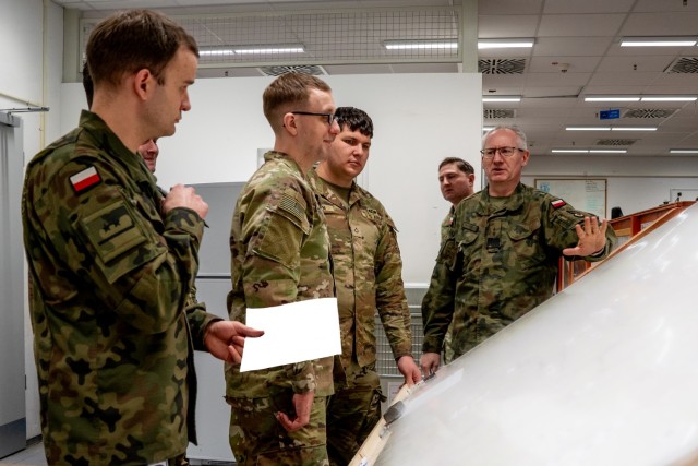 Maj. Michael Lubinski, deputy provost marshal of the 1st Cavalry Division, looks over a map of the local area with a Soldier and a Polish counterpart from 11th Armored Cavalry Division, during Exercise Combined Resolve 25-1 at the Joint Multinational Readiness Center on Hohenfels Training Area, Germany, Jan. 29, 2025. Combined Resolve 25-1 builds and validates combat readiness amongst participating NATO Allies and partner nations. (Parts of the image have been obscured for operational security) (U.S. Army illustration by Sgt. Jacob Nunnenkamp)