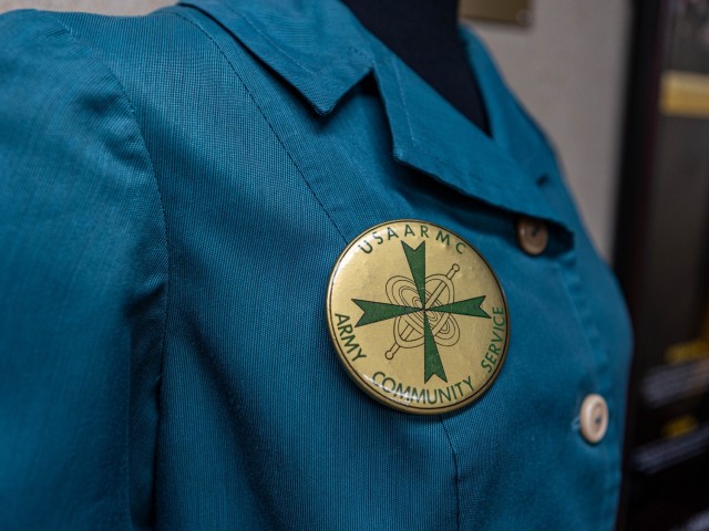 Lela Williams, donning her current Red Cross volunteer uniform, stands with her 1970s Army Community Service volunteer uniform at Fort Knox, Kentucky, Feb. 12, 2025. Williams has been a volunteer with the installation for over 50 years through ACS...