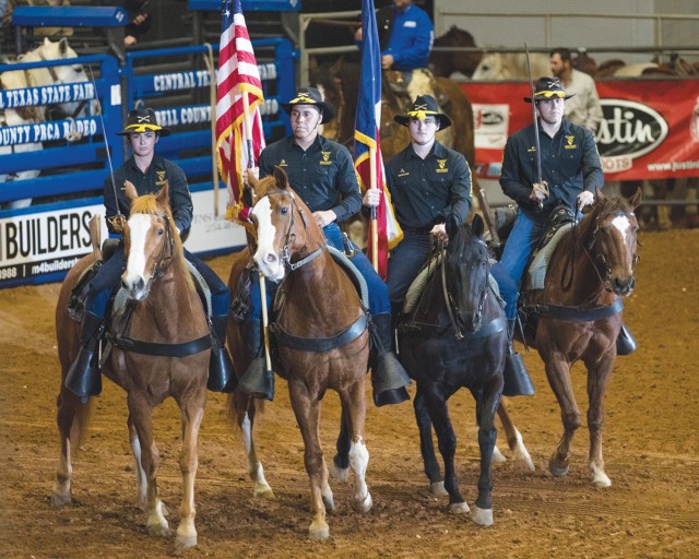 Four men sit on saddles atop horses as they stand in a line.