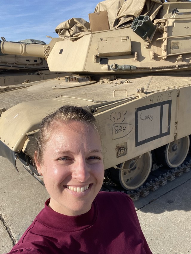 Jamie Todt, civil engineer at the Transportation Engineering Agency, stands in fron of a tank at Fort Riley, KS where she worked on Power Projection Platform route studies to ensure efficient and effective military deployments.