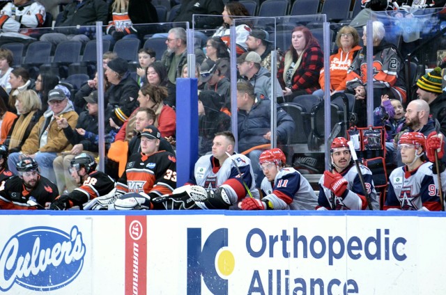 Capt. Micah Robbins, second from left, of Fort Leavenworth, Kansas, takes in the second-period action with Allen Americans players Kamerin Nault, Mark Duarte and Miko Matikka during the Allen Americans vs. KC Mavericks hockey game Feb. 19, 2025,...