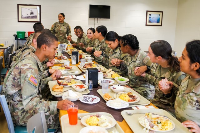 Fort Novosel trainees pray together before the Thanksgiving meal at the DFAC on Nov. 21, 2023.