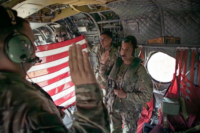 Cpl. Samantha Juarez, right, a patriot fire control enhanced operator/maintainer in the USARSOUTH fires and effects directorate (FED), recites the Oath of Enlistment during an in-flight reenlistment ceremony aboard in a Boeing CH-47 Chinook...