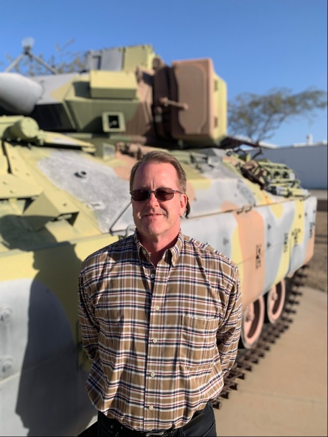 John Barczynski, safety engineer at Yuma Test Center at Yuma Proving Ground, Arizona, stands beside a M2A2 Bradley Fighting Vehicle.