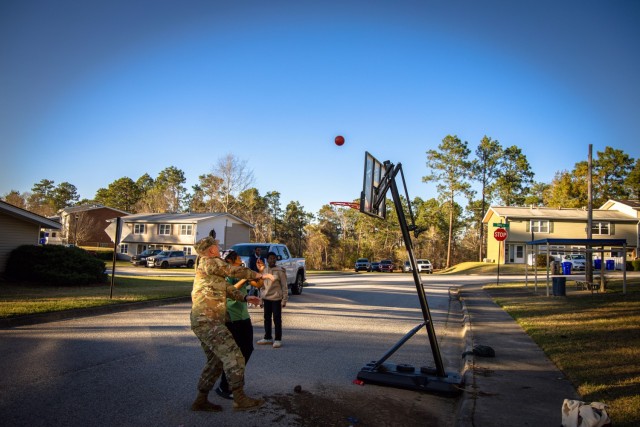 Command Sgt. Maj. Daniel Durette plays basketball with youth in Azalea Terrace during the Walking Town Hall on March 17, 2025. The informal setting allowed garrison leadership to connect with residents while fostering a sense of community.