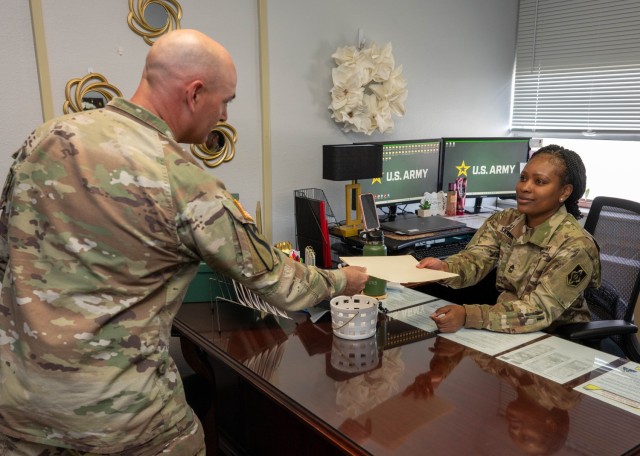 Master Sgt. LaShay Sanders, an inspector general NCO for the Maneuver Support Center of Excellence and Fort Leonard Wood, takes a folder from fellow IG NCO Master Sgt. Brandon Lacascio March 18 in Bldg. 315.