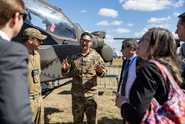 Australian Army Capt. Alex Paranthoine and U.S. Army Capt. Gregory Laboe, AH-64E Apache helicopter pilots assigned to 16th Combat Aviation Brigade, outlines the AH-64E’s key features and capabilities to members of a delegation at the 2025 Avalon...