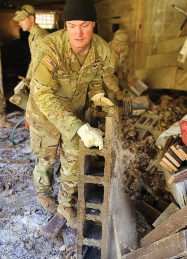 Soldiers in 1st Platoon, Alpha Company, 2nd Battalion, 502nd Infantry Regiment, 2nd Mobile Brigade Combat Team, 101st Airborne Division (Air Assault), remove debris so a local citizen can get to her tractor in western North Carolina on 11 October...