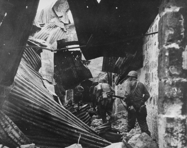 U.S. infantrymen make a house to house search for Japanese inside the ruins of the walled city, from which they had liberated hundreds of Filipino prisoners, 23 February 1945.
