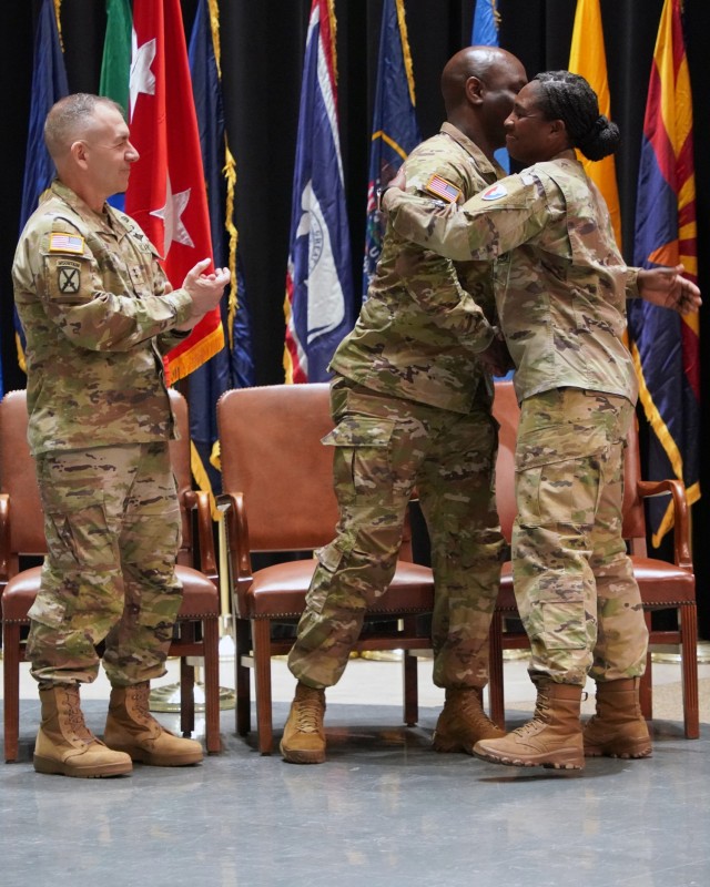 Maj. Gen. Michael B. Lalor, commanding general of TACOM, looks on as incoming Command Sgt. Major Kofie Primus and outgoing Command Sgt. Maj. Kendra St Helen share a hug.