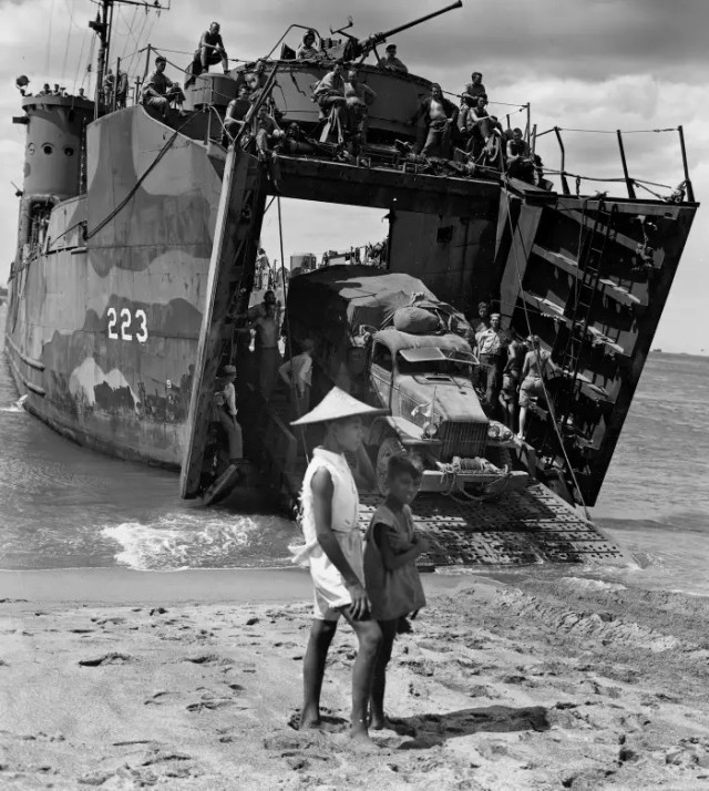 Two Filipino children watching US Navy ships bringing troops and supplies into the west coast of Luzon in January 1945.