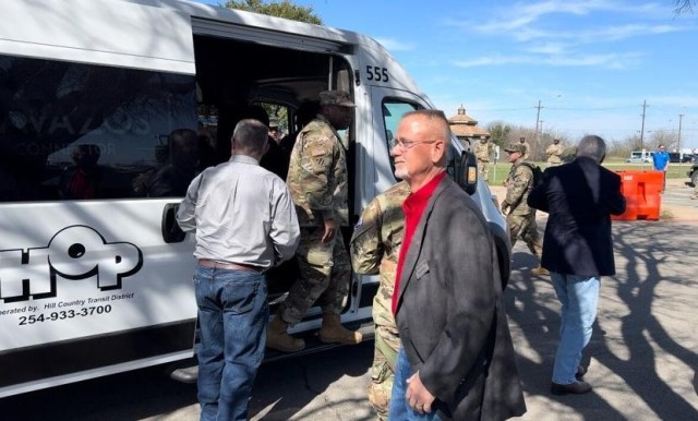 People exit and enter a large, white passenger van.