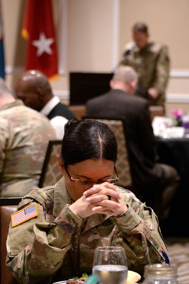 Maj. Yaimiset Perez, Headquarters, Midwest Joint Regional Correctional Facility Battalion (Corrections), bows her head and clasps her hands as Chaplain (Col.) Matt Atkins, Mission Command Training Program religious support observer, coach/trainer...