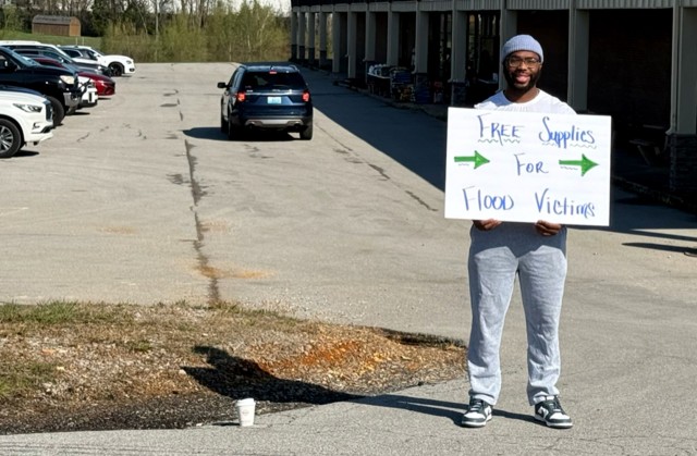 A man holds a sign that reads, &#34;Free Supplies for Flood Victims.&#34;